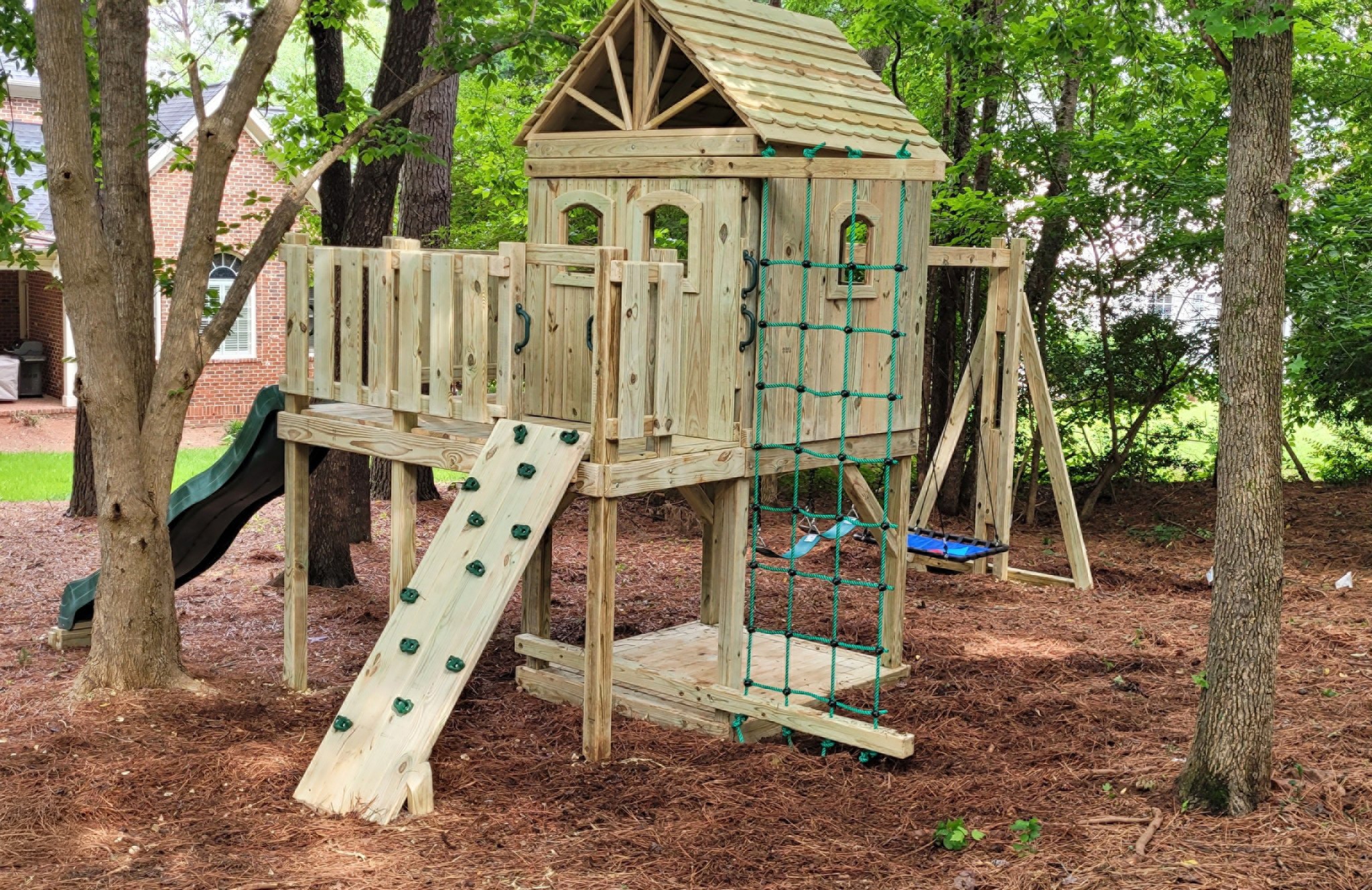 17. Vibrant Turquoise Slide Amidst Rustic Wooden Forts and Twisting Vines