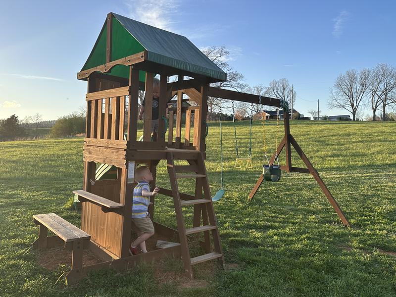 12. Vibrant Rainbow Slide and Turquoise Swing Set Amidst Lush Greenery