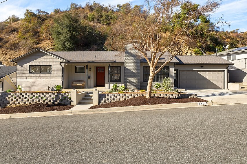 16. Ranch Style Home with Vibrant Red Door and Sunlit Pathway