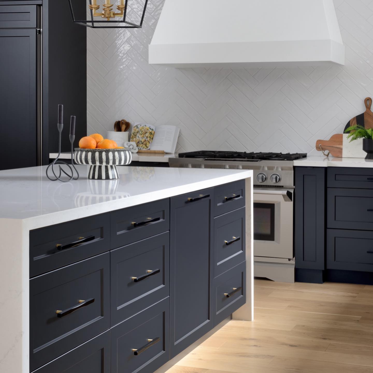 5. White Quartz Herringbone Backsplash with Brass Accents and Industrial Shelving