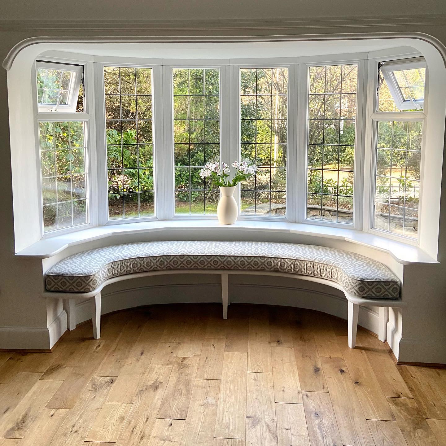 2. the Crimson Curtain Framed Bay Window with Geometric Pillow Accents