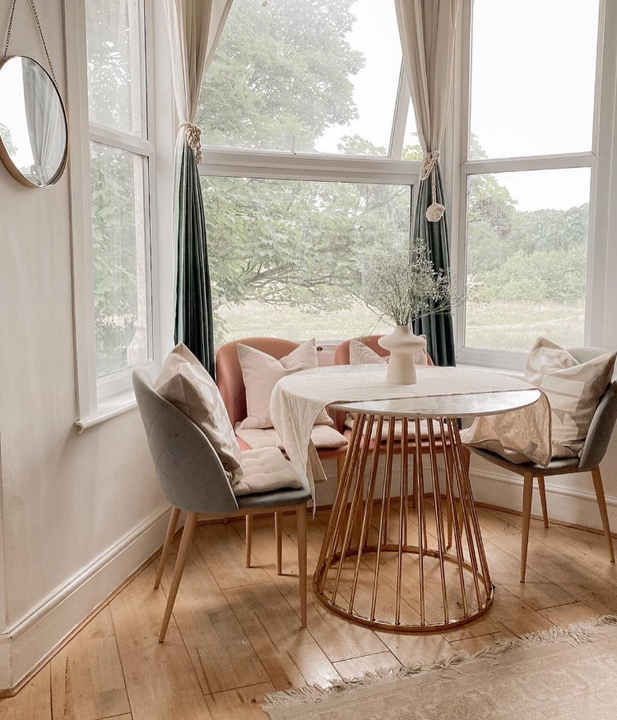 9. Bay Window Bookshelf with Geometric Patterned Cushions and Sunlight Filtering Through Sheer Drapes