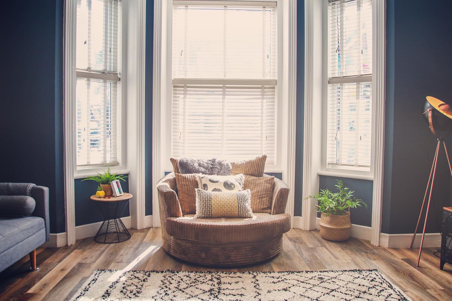 30. Vibrant Fuschia Cushions Against Soft Blue Drapes In a Sunlit Bay Window