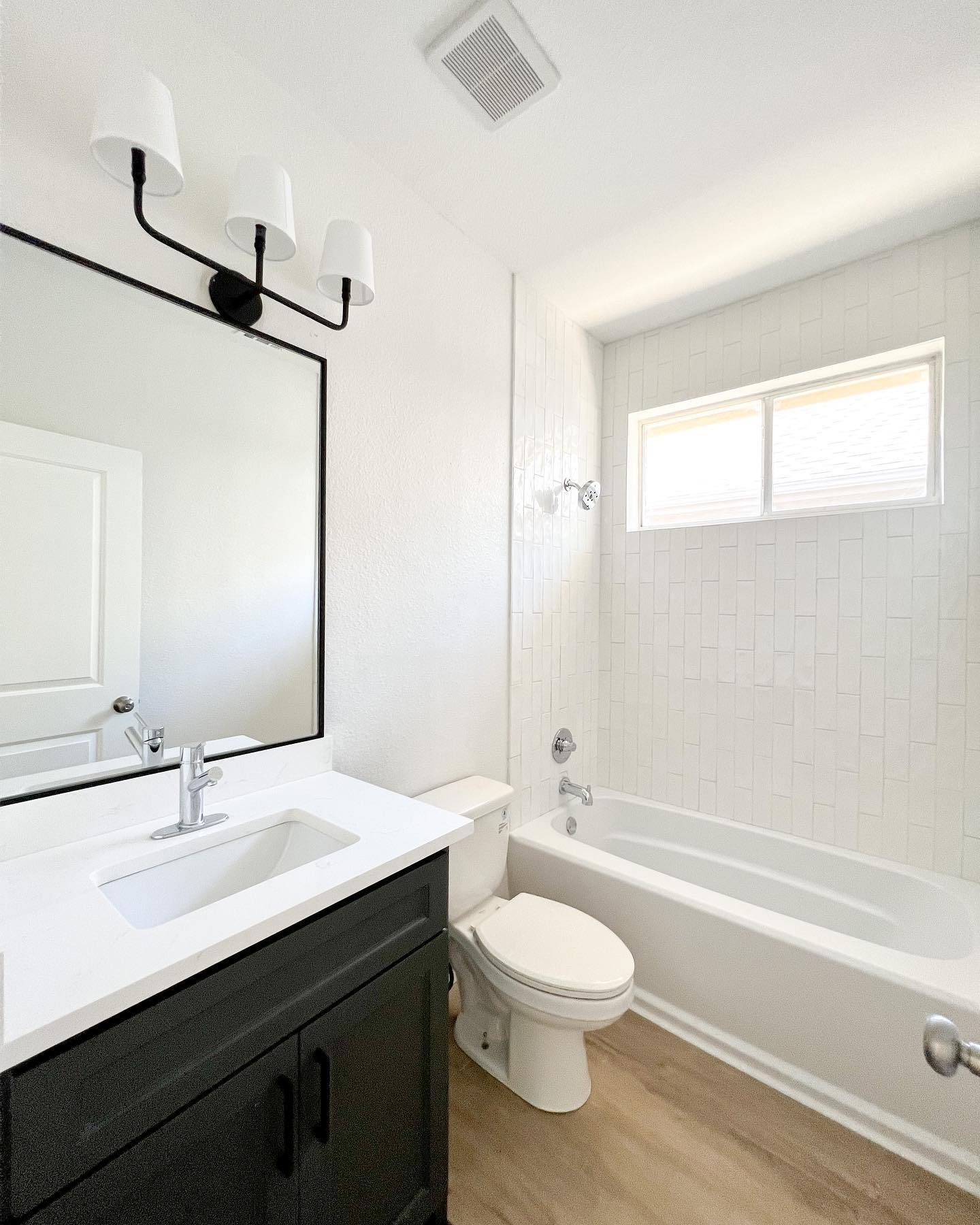 5. Sleek Black and White Mosaic Tiled Tub Surround with Floating Shelf Accent