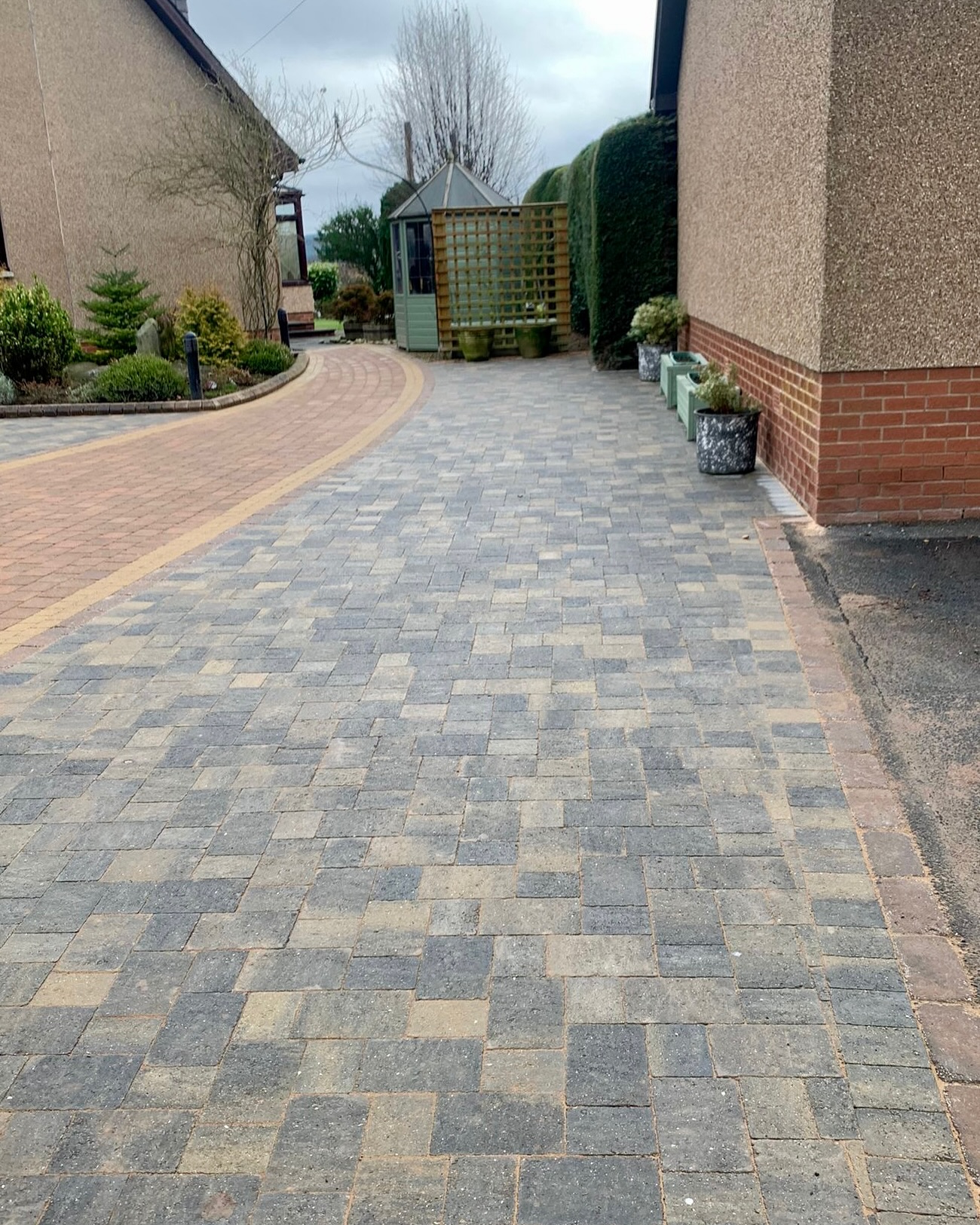18. Crimson Gravel Pathway with Stone Pillars and Solar Lamps In a Modern Driveway Setting