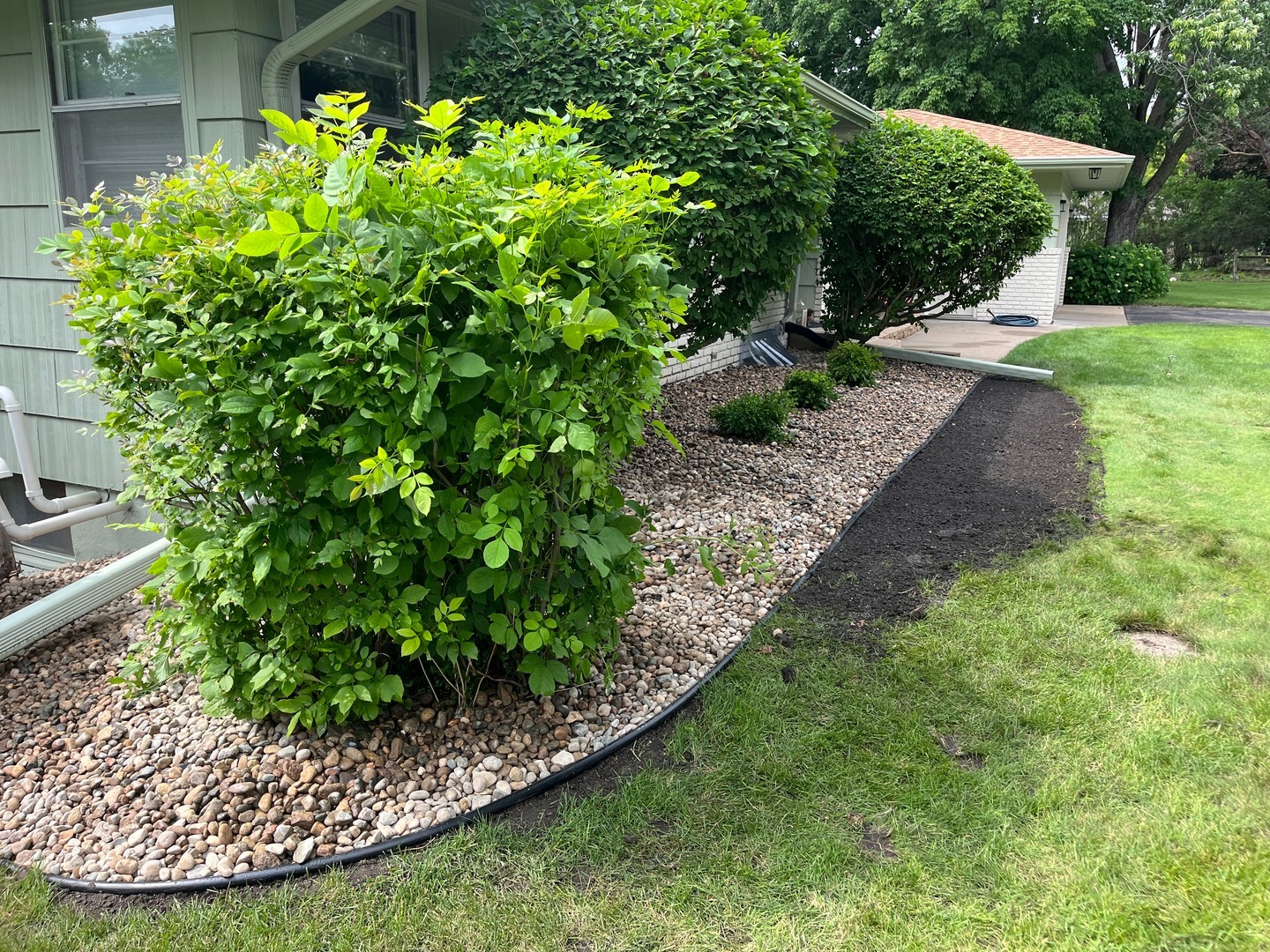 12. River Pebbles Cascade Over a Sunlit Boulder In a Minimalist Garden Setting