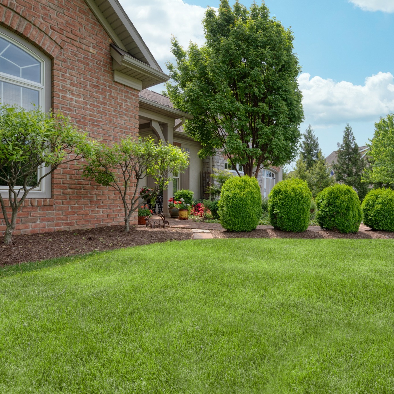 20. Lush Boxwood Spheres and Variegated Holly Accents Flanking a Victorian Porch